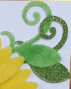 Petal, leaf and swirl shapes covered with Sticky Roll, cut on the Scan N Cut, and decorated with yellow and green flock, and green glitter