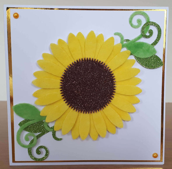 A card with a handmade sunflower, made from yellow flock and bronze glitter